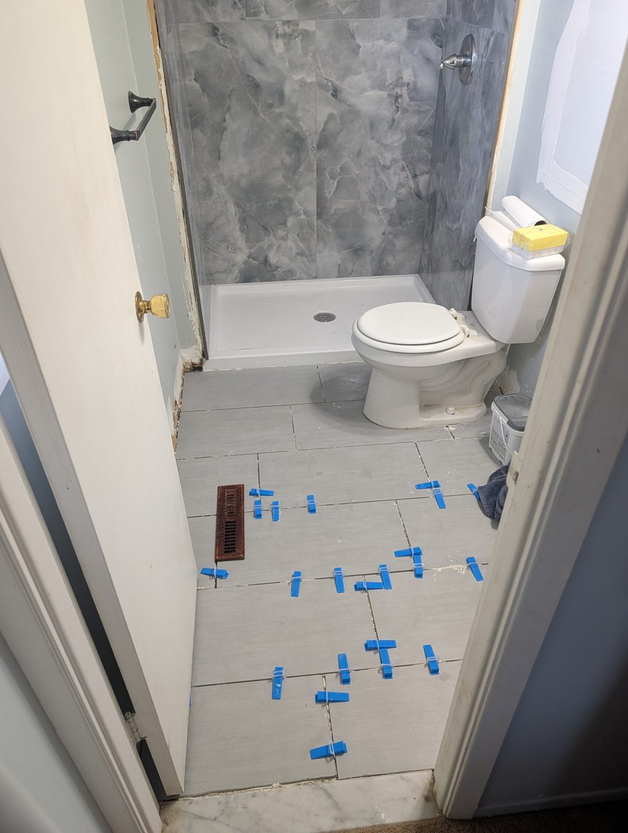 Bathroom remodel in progress with a marble-look shower surround, new shower pan, and gray floor tile