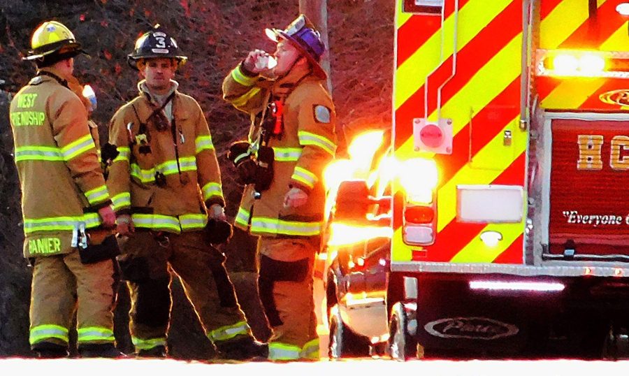 Volunteer firefighters on scene beside a fire engine
